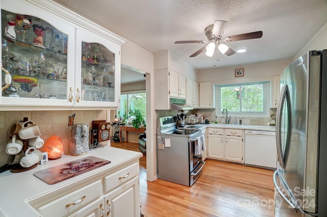 kitchen featuring light wood-type flooring, white cabinets, white dishwasher, electric stove, and stainless steel fridge