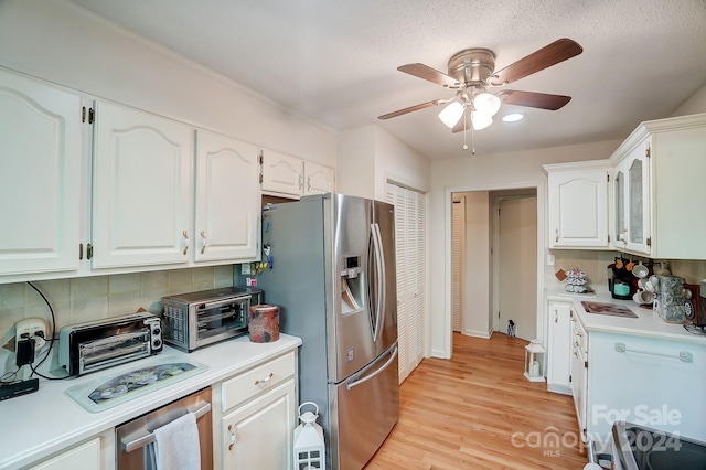 kitchen with ceiling fan, stainless steel appliances, white cabinets, decorative backsplash, and light hardwood / wood-style flooring