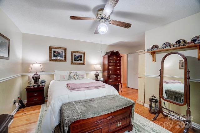 bedroom featuring light wood-type flooring, ceiling fan, and a textured ceiling