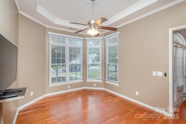 unfurnished dining area featuring crown molding, a tray ceiling, ceiling fan, and hardwood / wood-style flooring