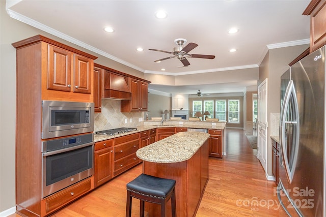 kitchen featuring a kitchen island, appliances with stainless steel finishes, a kitchen bar, custom exhaust hood, and light hardwood / wood-style floors