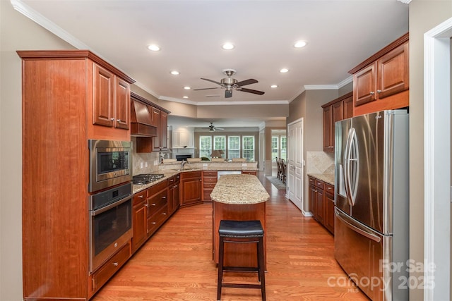 kitchen with a kitchen island, appliances with stainless steel finishes, a kitchen breakfast bar, kitchen peninsula, and light hardwood / wood-style flooring