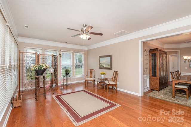 living area with hardwood / wood-style flooring, crown molding, and ceiling fan with notable chandelier