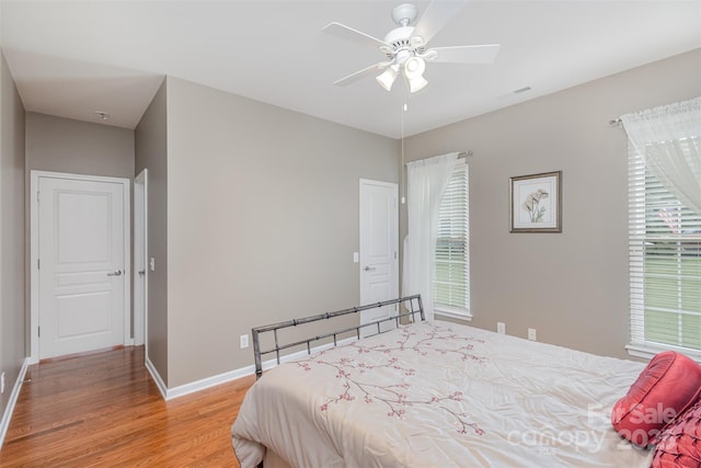 bedroom with multiple windows, wood-type flooring, and ceiling fan