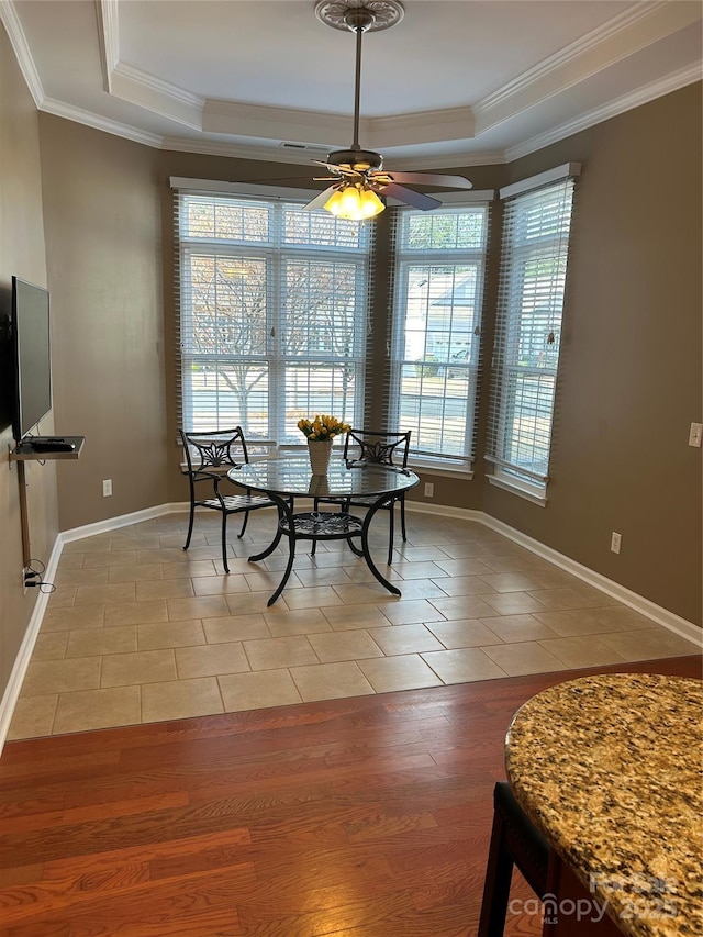 tiled dining space with crown molding, ceiling fan, and a tray ceiling