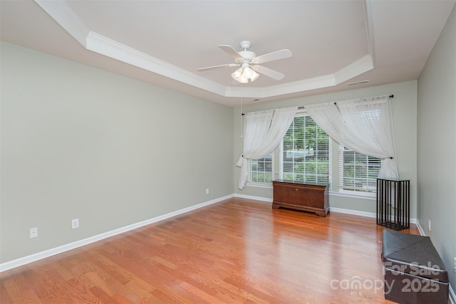 spare room featuring crown molding, ceiling fan, a raised ceiling, and light wood-type flooring