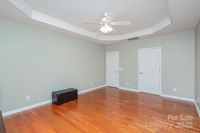 spare room with hardwood / wood-style flooring, ornamental molding, ceiling fan, and a tray ceiling