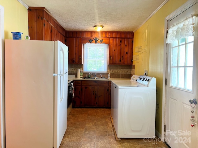 washroom with washing machine and clothes dryer, crown molding, sink, and a textured ceiling