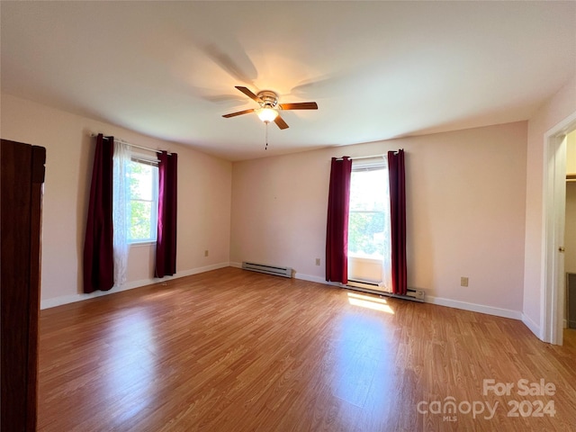 empty room with light hardwood / wood-style floors, ceiling fan, and a baseboard heating unit