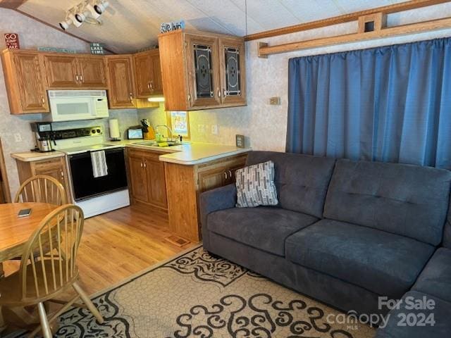 kitchen featuring vaulted ceiling, white appliances, light hardwood / wood-style floors, and sink