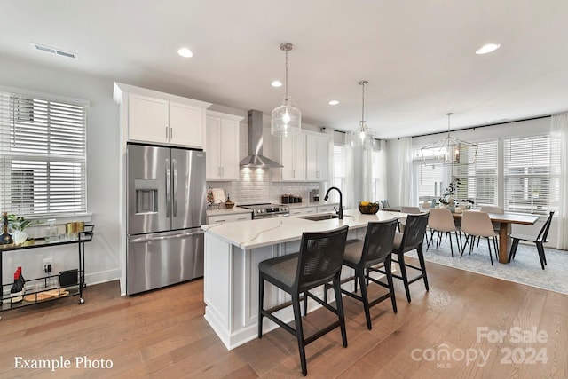 kitchen featuring appliances with stainless steel finishes, plenty of natural light, hardwood / wood-style flooring, and wall chimney exhaust hood