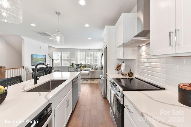 kitchen featuring stainless steel appliances, dark hardwood / wood-style flooring, wall chimney exhaust hood, sink, and pendant lighting