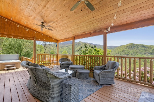 wooden deck with a hot tub, ceiling fan, and a mountain view