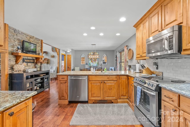 kitchen featuring sink, kitchen peninsula, hardwood / wood-style flooring, and appliances with stainless steel finishes