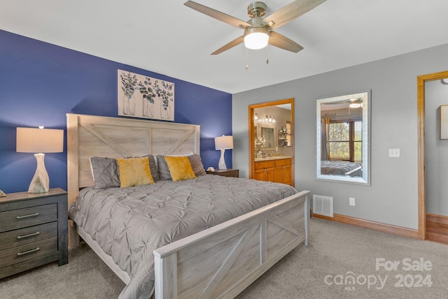 bedroom featuring light colored carpet, ensuite bathroom, and ceiling fan