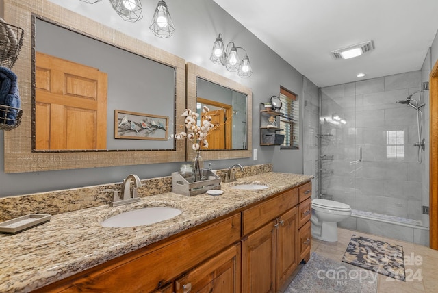 bathroom featuring dual sinks, tile flooring, vanity with extensive cabinet space, a shower with shower door, and toilet