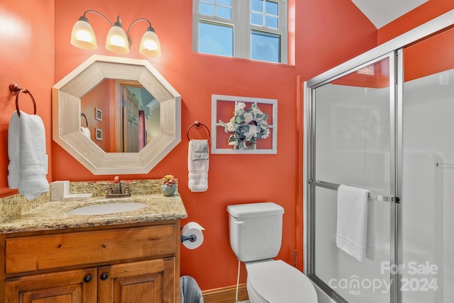 bathroom featuring a shower with door, vanity, and toilet