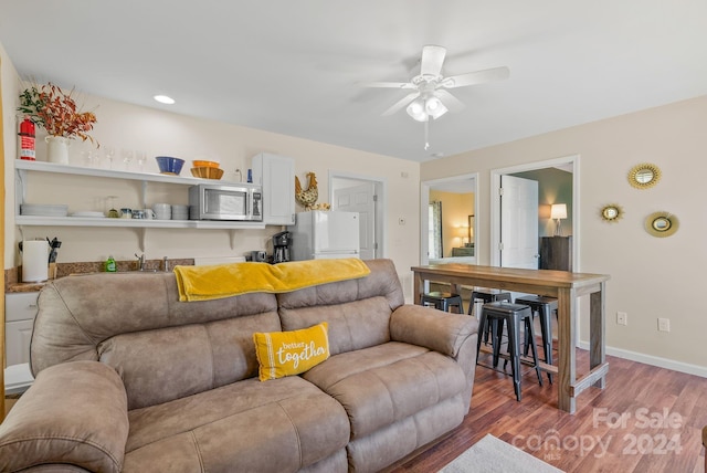 living room featuring ceiling fan and dark wood-type flooring