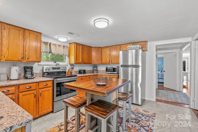 kitchen featuring stainless steel appliances, light stone counters, and light tile flooring