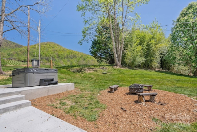 view of yard featuring a mountain view, a fire pit, and a hot tub