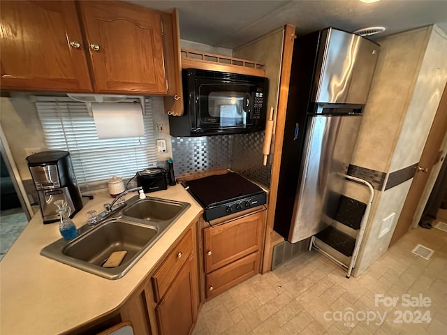 kitchen with backsplash, sink, black appliances, and light tile floors