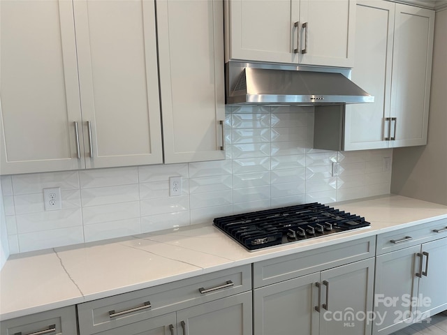 kitchen featuring backsplash, light stone counters, black gas stovetop, and gray cabinetry