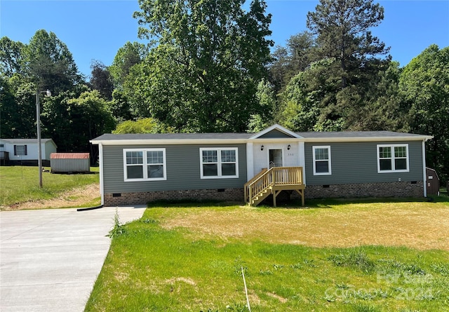 manufactured / mobile home with a front lawn and a storage shed