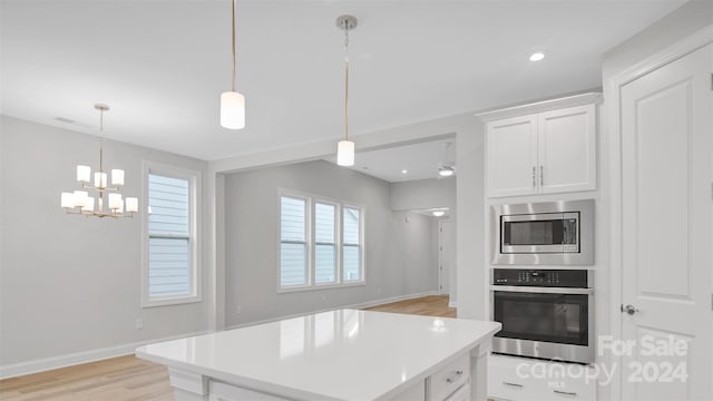 kitchen with stainless steel appliances, pendant lighting, and white cabinets