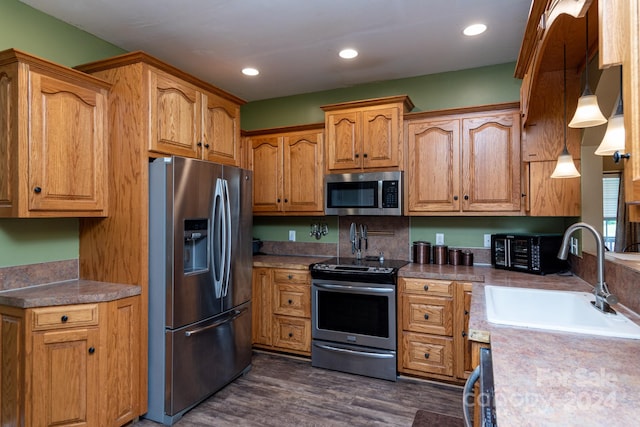 kitchen featuring dark hardwood / wood-style floors, sink, stainless steel appliances, and pendant lighting