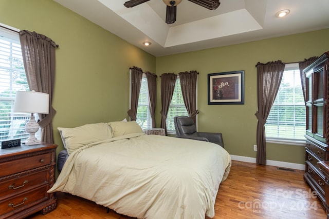 bedroom featuring a raised ceiling, ceiling fan, and hardwood / wood-style flooring