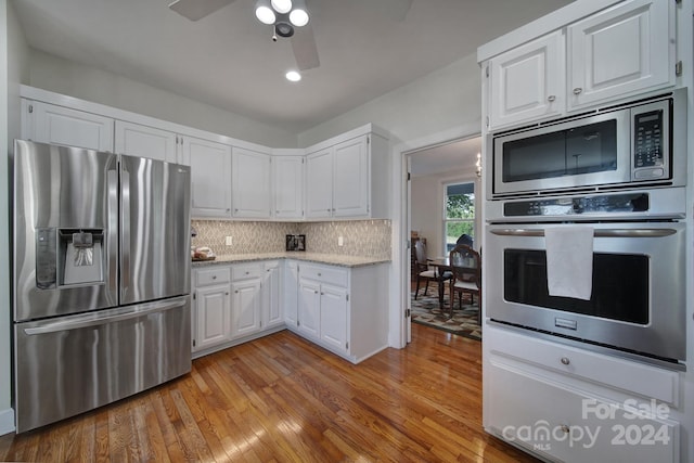 kitchen with backsplash, light hardwood / wood-style flooring, stainless steel appliances, ceiling fan, and white cabinetry