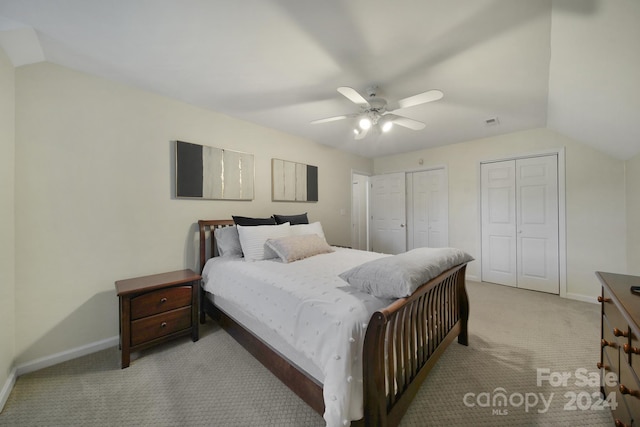 carpeted bedroom with ceiling fan, vaulted ceiling, and multiple closets