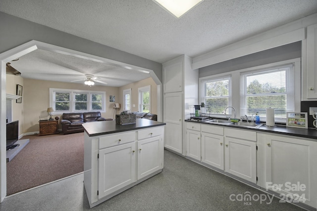 kitchen with ceiling fan, a textured ceiling, white cabinets, sink, and carpet floors