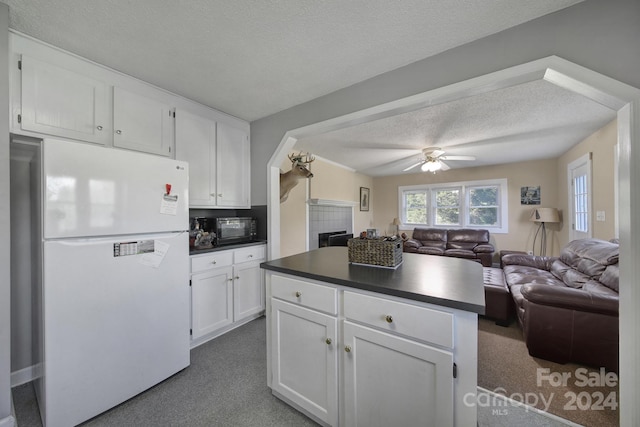 kitchen featuring ceiling fan, white cabinetry, white fridge, and carpet floors