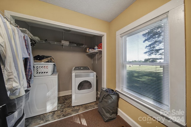 clothes washing area with washer and clothes dryer, dark carpet, and a textured ceiling