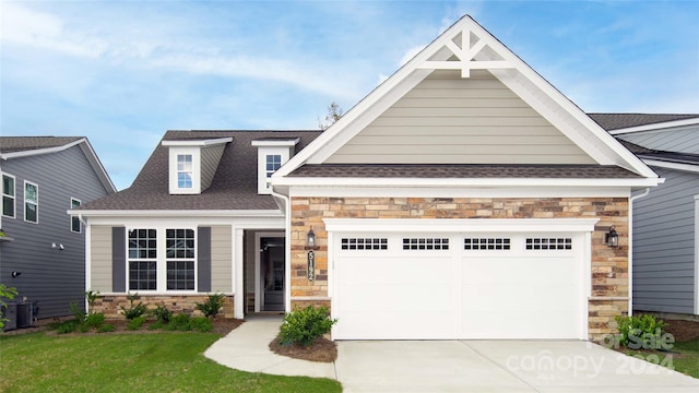 craftsman-style home featuring a garage, central AC, and a front yard