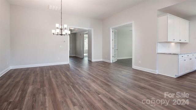 unfurnished dining area featuring dark wood-type flooring and a chandelier