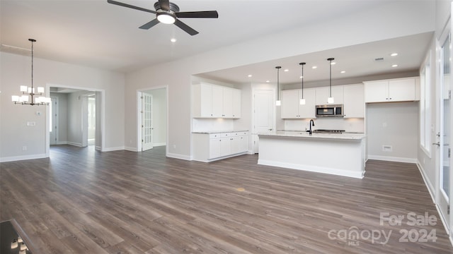 kitchen featuring white cabinetry, a center island with sink, ceiling fan with notable chandelier, hanging light fixtures, and dark hardwood / wood-style flooring