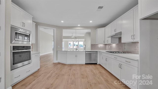 kitchen with backsplash, white cabinetry, sink, and stainless steel appliances