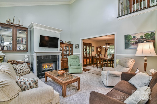 living room with crown molding, a towering ceiling, a notable chandelier, and a fireplace