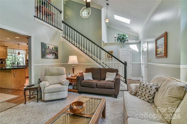 living room featuring high vaulted ceiling, a skylight, crown molding, and hardwood / wood-style flooring