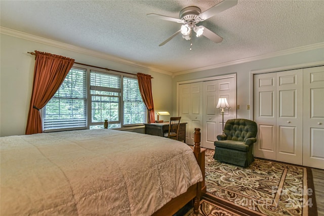 bedroom with ceiling fan, crown molding, multiple closets, and a textured ceiling