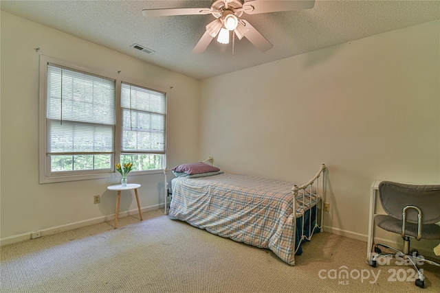 bedroom with carpet flooring, ceiling fan, and a textured ceiling