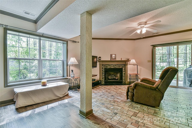 living room featuring a fireplace, a wealth of natural light, ceiling fan, and ornamental molding