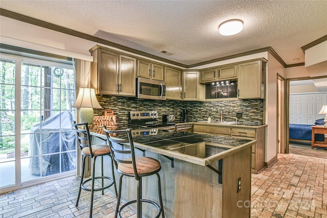 kitchen with sink, tasteful backsplash, crown molding, stainless steel appliances, and a kitchen breakfast bar