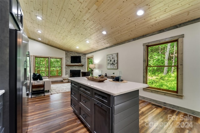 kitchen with a kitchen island, a stone fireplace, wood ceiling, and dark wood-type flooring