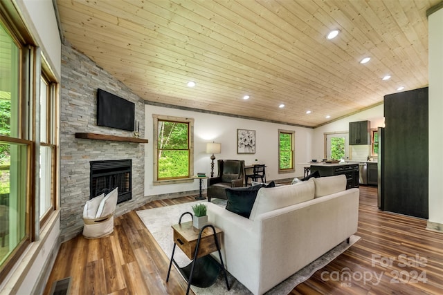 living room featuring hardwood / wood-style floors, vaulted ceiling, wood ceiling, and a stone fireplace