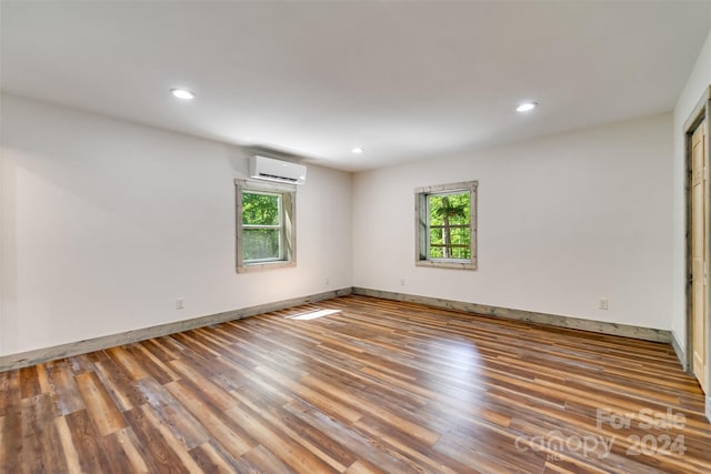 empty room with hardwood / wood-style floors, a healthy amount of sunlight, and a wall mounted air conditioner