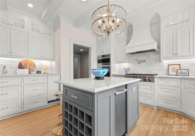 kitchen with hanging light fixtures, tasteful backsplash, beamed ceiling, custom range hood, and stainless steel appliances