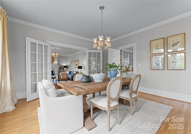 dining area featuring ornamental molding, light wood-type flooring, and a notable chandelier